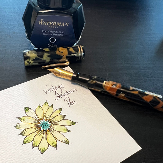 Fountain pen with a bottle of ink and a watercolor flower