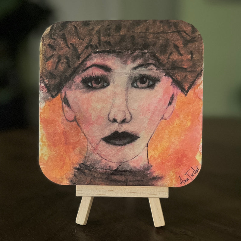 Ruby is a 5x5 mixed-media art board from the Women + Words series — a collectible piece with a hidden message and mini easel.